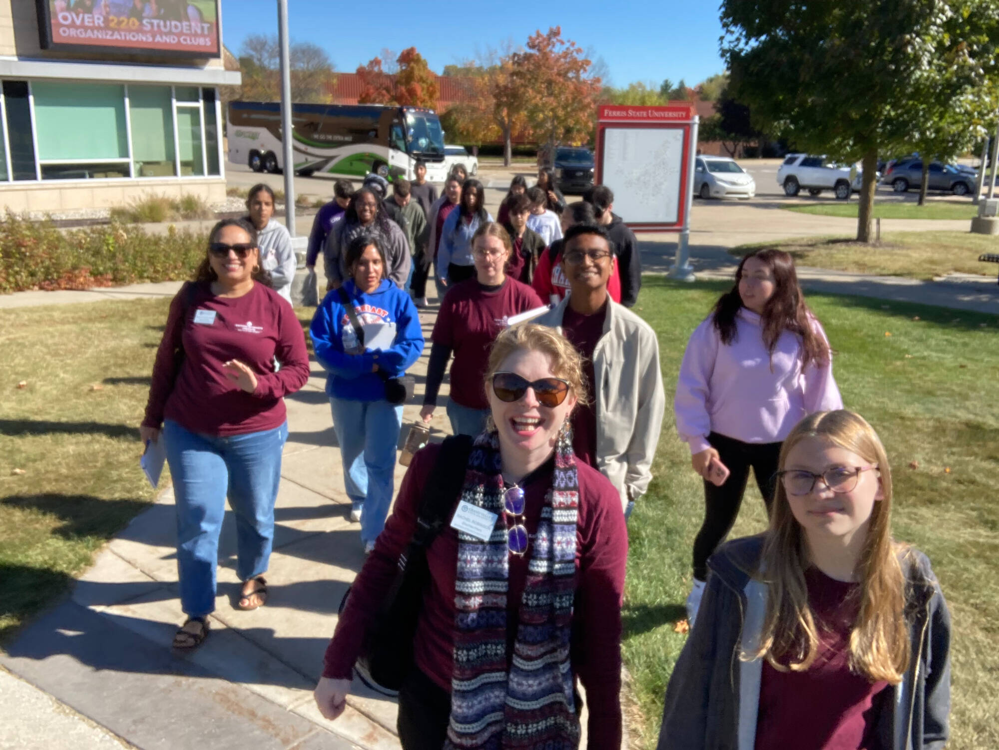 A group of students and staff walking toward the camera on a nice day.